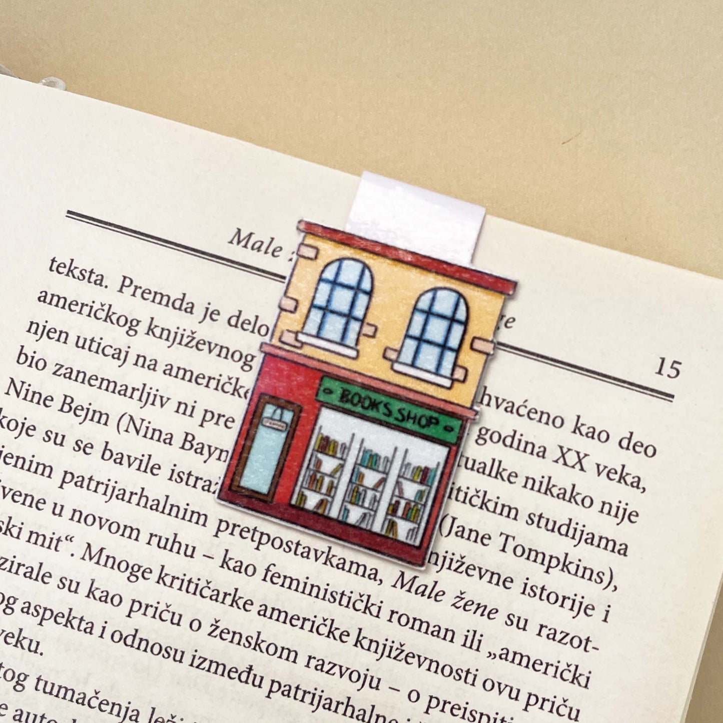Book with a bookmark featuring a illustration of a bookshop on an open page.