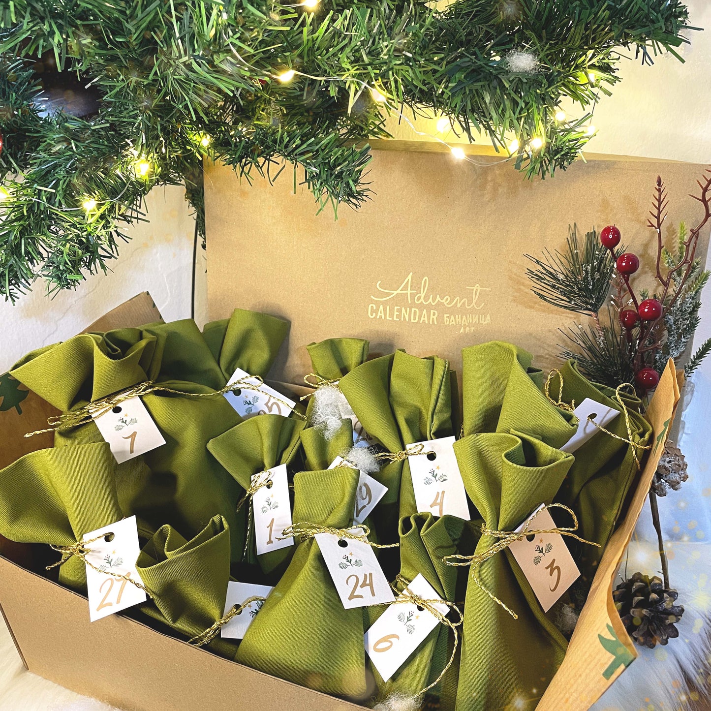 Advent calendar with green bags and numbered tags under a decorated Christmas tree.