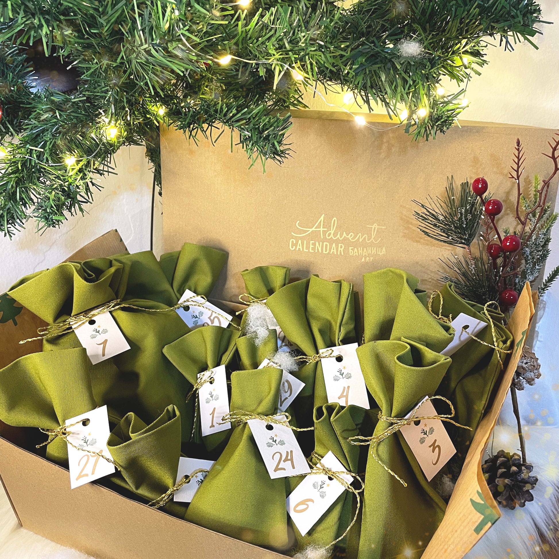Advent calendar with green bags and numbered tags under a decorated Christmas tree.
