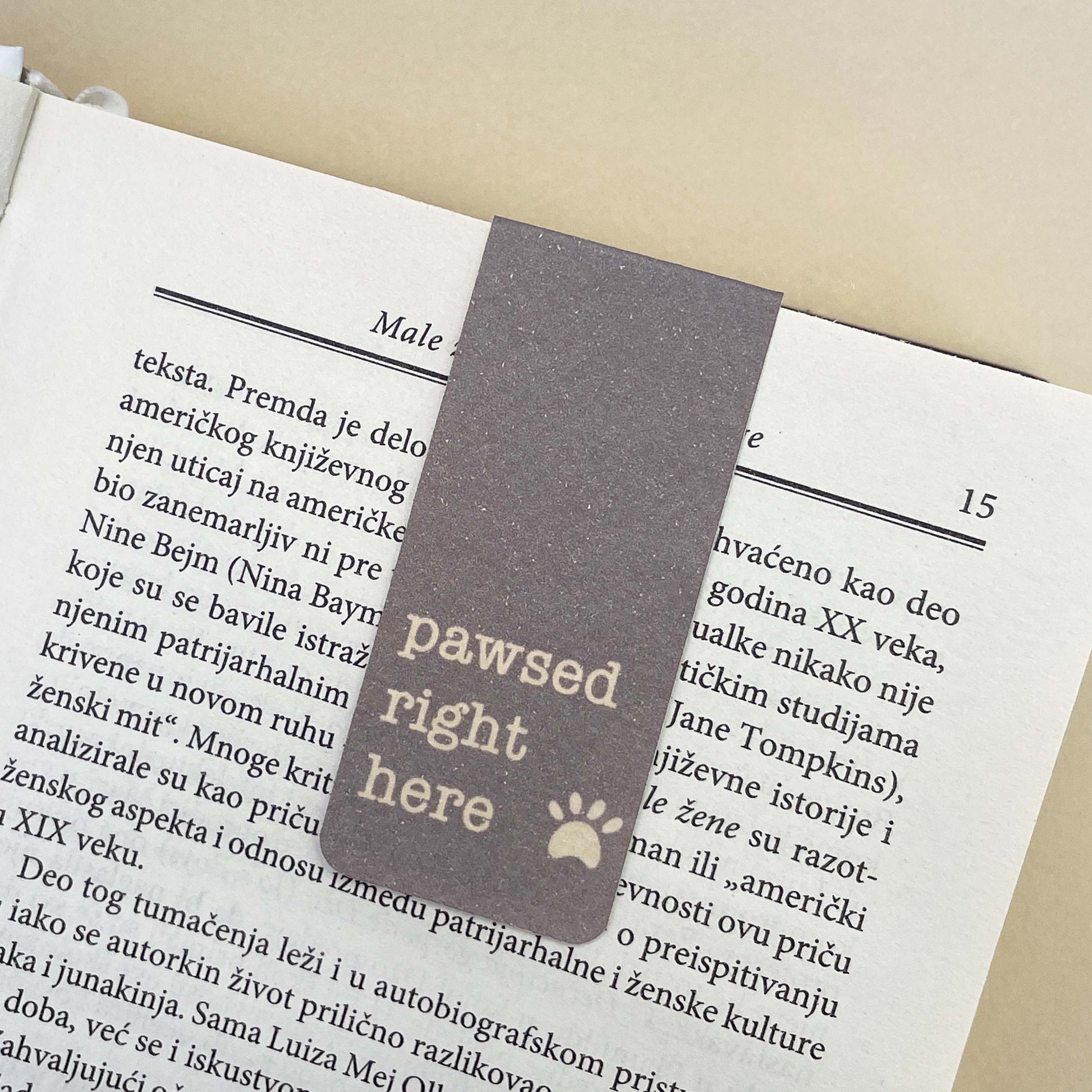 Bookmark with 'pawsed right here' text on a book page